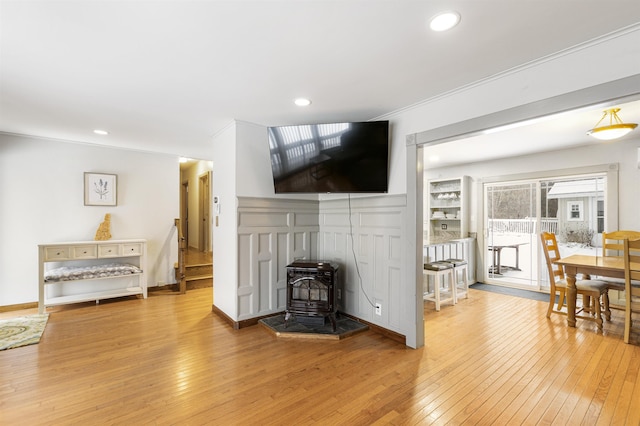 living room with a wood stove, crown molding, and hardwood / wood-style flooring