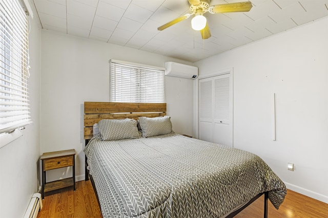 bedroom with ceiling fan, dark wood-type flooring, a wall mounted AC, and a baseboard heating unit