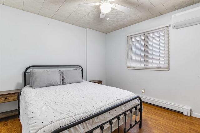 bedroom featuring a baseboard radiator, an AC wall unit, ceiling fan, and hardwood / wood-style flooring