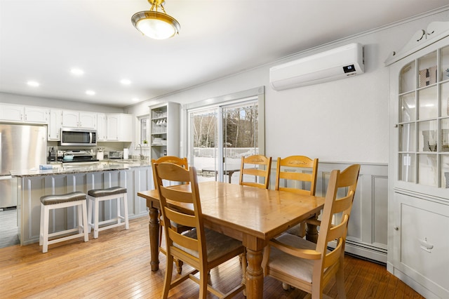 dining room with light hardwood / wood-style floors, an AC wall unit, and sink