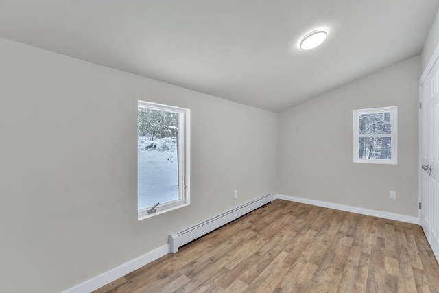 spare room with light wood-type flooring, baseboard heating, and vaulted ceiling