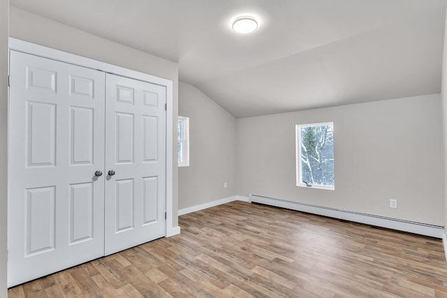 bonus room with light wood-type flooring, baseboard heating, and vaulted ceiling