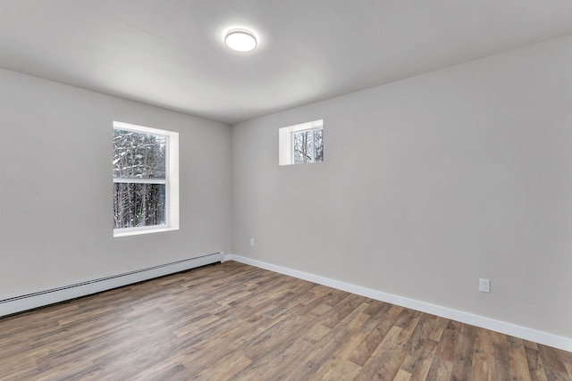 unfurnished room featuring hardwood / wood-style flooring and a baseboard heating unit