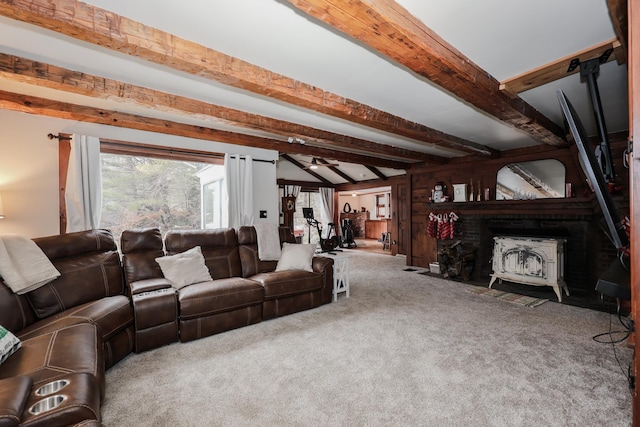 carpeted living room featuring a wood stove and beamed ceiling