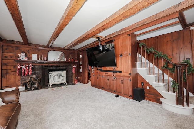 carpeted living room with a fireplace, beam ceiling, and wood walls