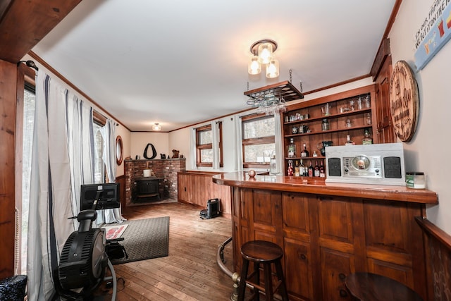 bar featuring a wood stove, crown molding, built in shelves, and light wood-type flooring