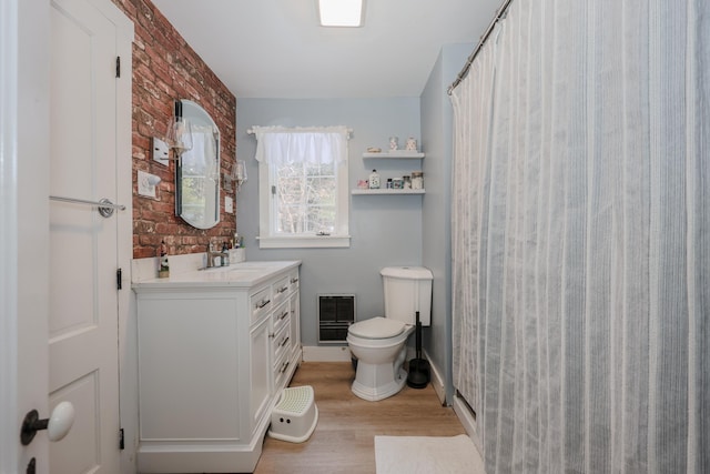 bathroom featuring brick wall, a shower with curtain, vanity, hardwood / wood-style flooring, and toilet