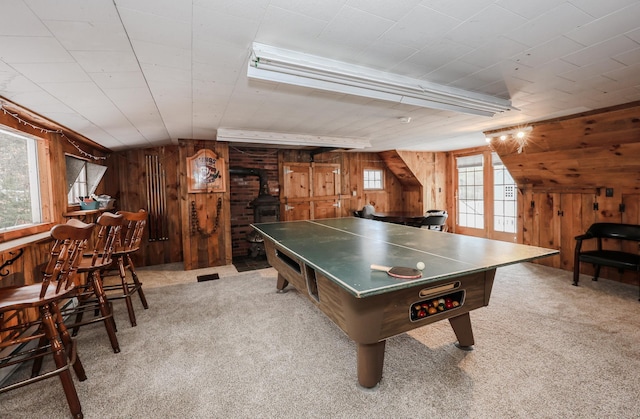 game room featuring carpet flooring, vaulted ceiling with beams, a wood stove, and wooden walls