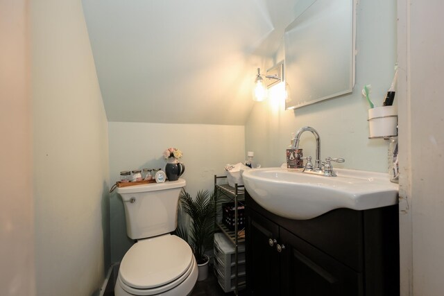 bathroom featuring toilet, vanity, and vaulted ceiling