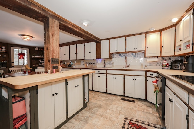 kitchen with butcher block countertops, backsplash, sink, and white cabinets