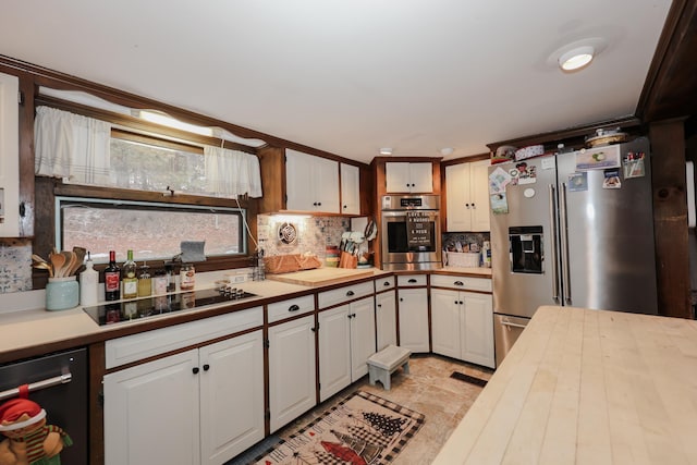 kitchen with decorative backsplash, white cabinets, and stainless steel appliances