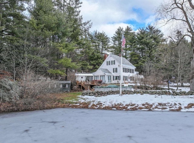 snow covered rear of property with a deck