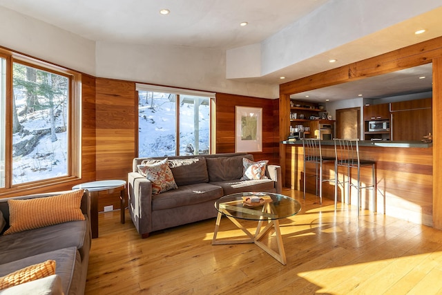 living room with light hardwood / wood-style floors and wooden walls