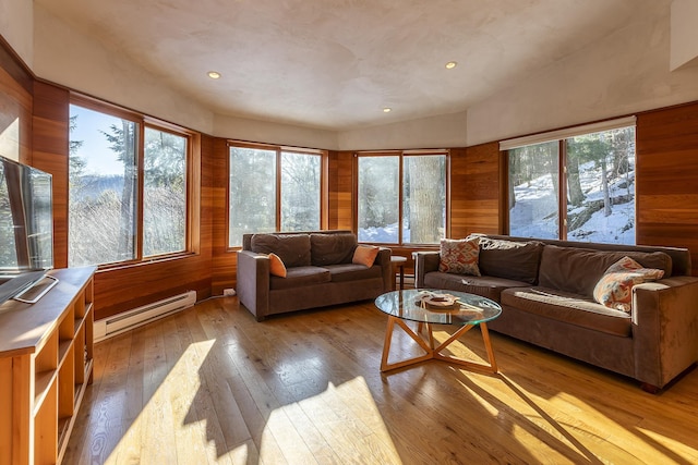 living room featuring a healthy amount of sunlight, light wood-type flooring, a baseboard radiator, and wooden walls