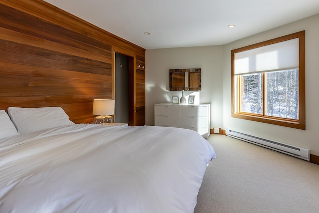 carpeted bedroom with baseboard heating and wooden walls