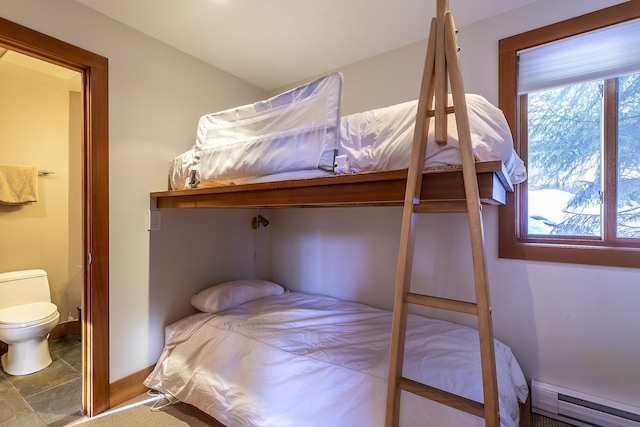 bedroom featuring ensuite bath and a baseboard heating unit