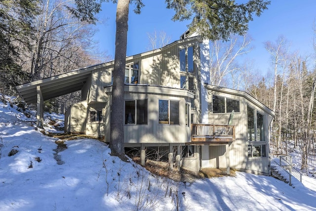 snow covered back of property featuring a deck