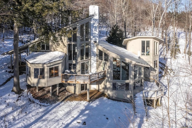 snow covered rear of property featuring a wooden deck