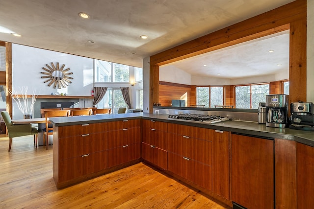 kitchen featuring kitchen peninsula, light hardwood / wood-style flooring, lofted ceiling, and stainless steel gas cooktop