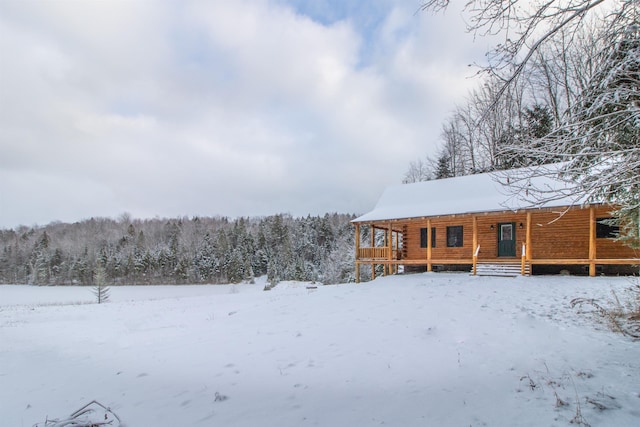 snow covered house featuring a forest view