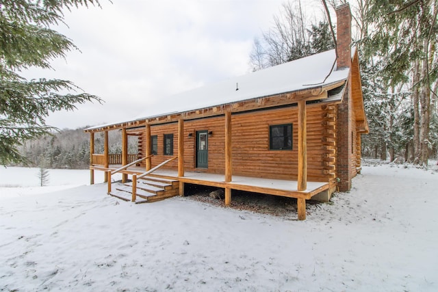 exterior space featuring a chimney, covered porch, and log exterior