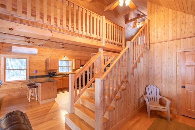 staircase featuring high vaulted ceiling, a wall mounted AC, wood finished floors, and wooden walls