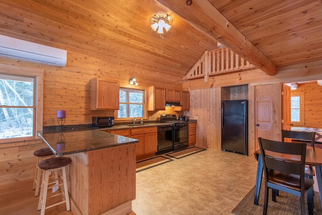 kitchen featuring a peninsula, black appliances, a sink, and wood walls