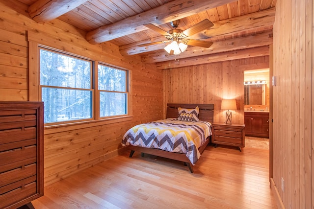 bedroom with light wood finished floors, beam ceiling, and wood walls