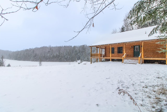 snow covered house with a view of trees