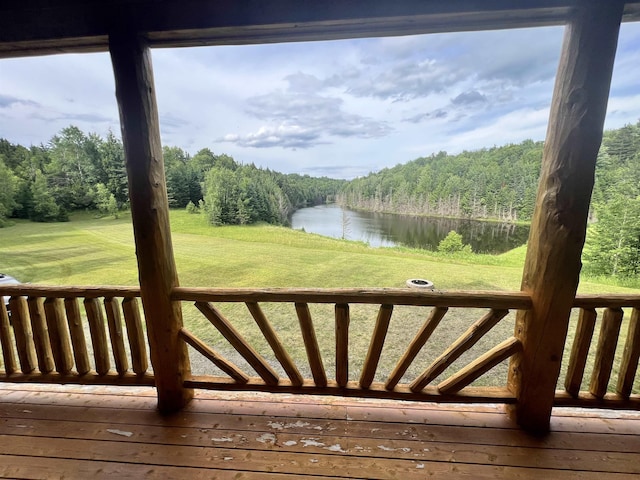 wooden terrace featuring a water view, a lawn, and a wooded view