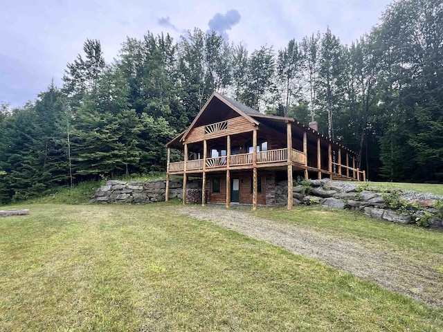 view of front of property with a front yard, a wooden deck, and a forest view