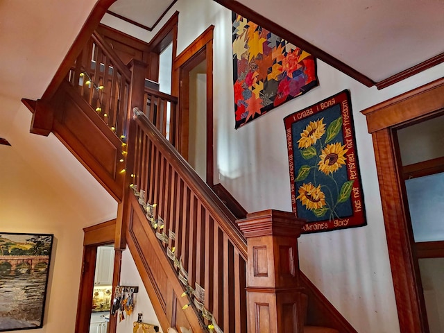 staircase featuring a towering ceiling and crown molding