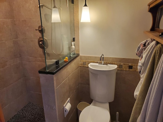 bathroom featuring a tile shower, tile walls, and toilet