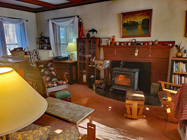 living area featuring beam ceiling, carpet floors, and a wood stove