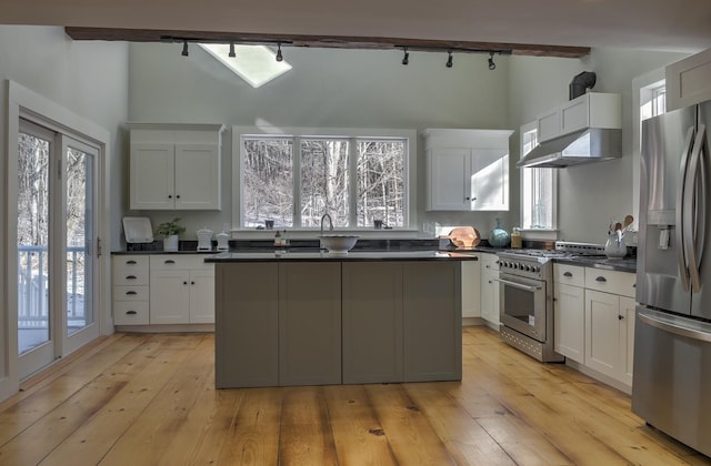 kitchen with beam ceiling, stainless steel appliances, light hardwood / wood-style floors, and white cabinets