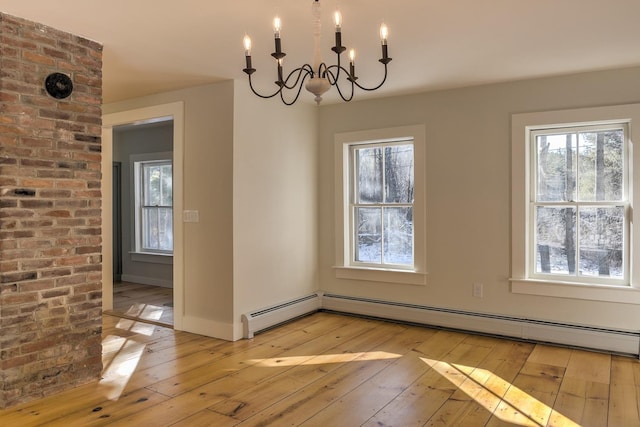 unfurnished dining area featuring a baseboard heating unit, light hardwood / wood-style flooring, and a chandelier