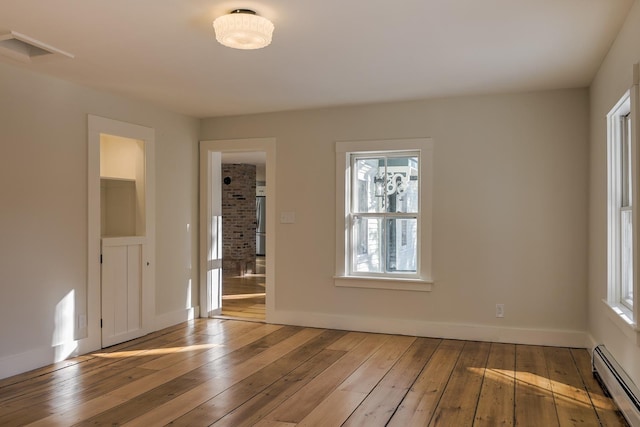 empty room with light hardwood / wood-style floors and a baseboard heating unit