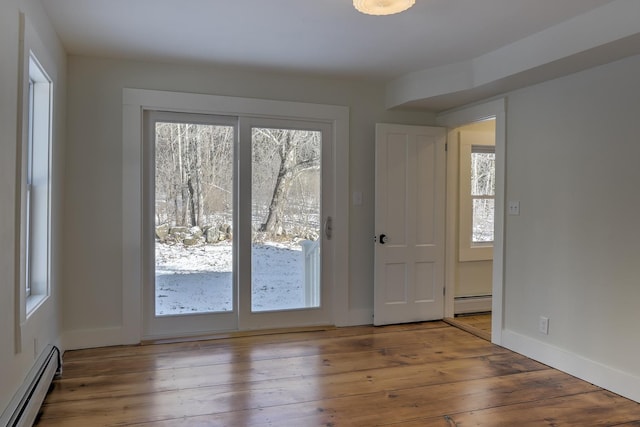 doorway to outside with hardwood / wood-style flooring, a baseboard radiator, and plenty of natural light