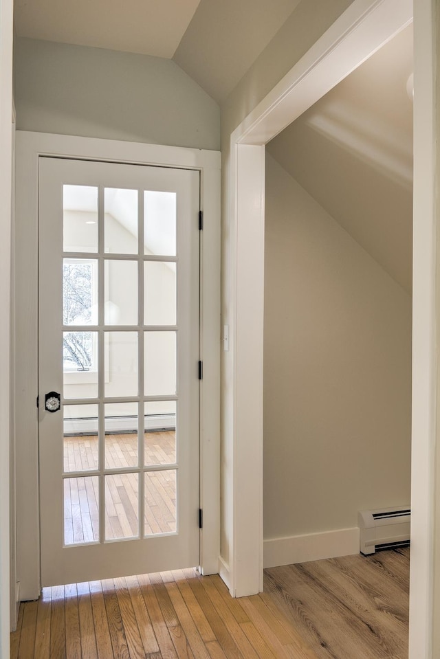 doorway to outside featuring light hardwood / wood-style flooring, vaulted ceiling, and baseboard heating