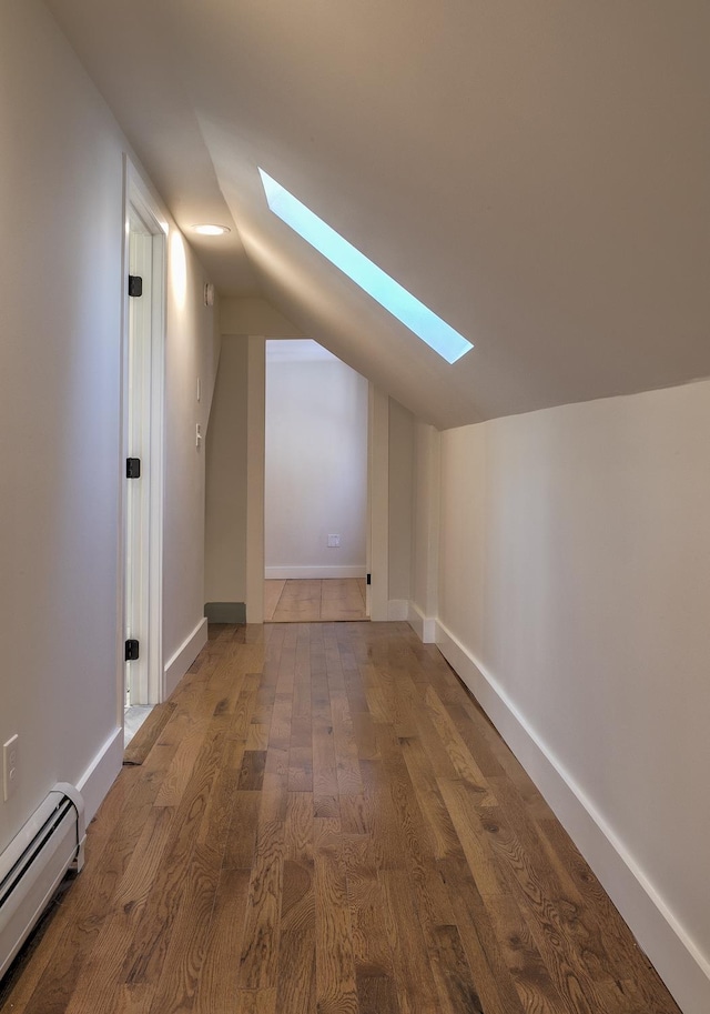 bonus room featuring a baseboard heating unit, wood-type flooring, and vaulted ceiling with skylight