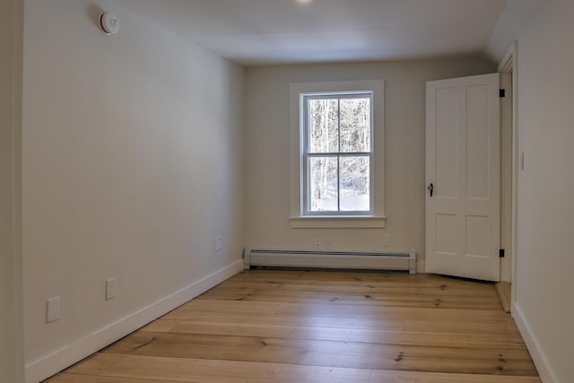 empty room with baseboard heating and light hardwood / wood-style floors