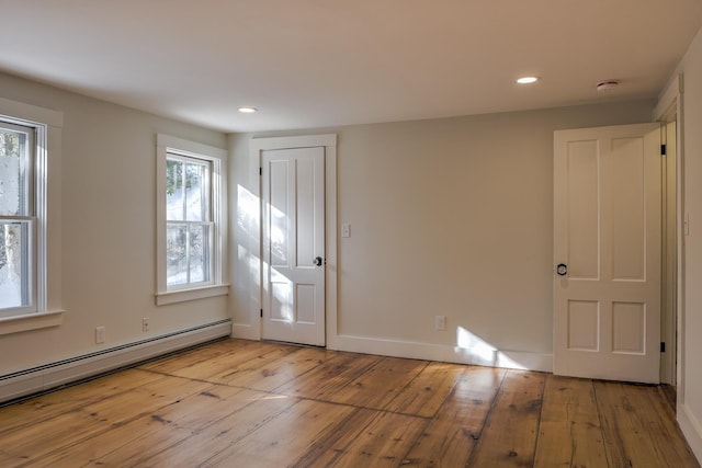 interior space featuring a baseboard heating unit and light wood-type flooring