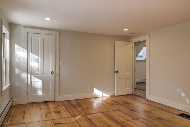 interior space featuring a closet, light hardwood / wood-style flooring, baseboard heating, and a skylight