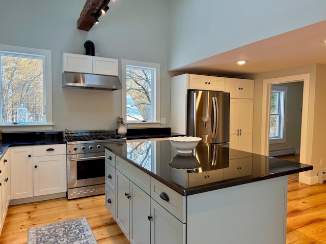 kitchen with stainless steel appliances, a wealth of natural light, ventilation hood, white cabinets, and a kitchen island