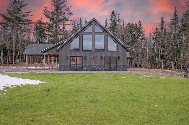 back house at dusk featuring a lawn