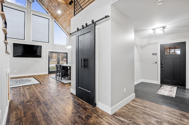 foyer entrance with a barn door, dark hardwood / wood-style floors, high vaulted ceiling, and wooden ceiling