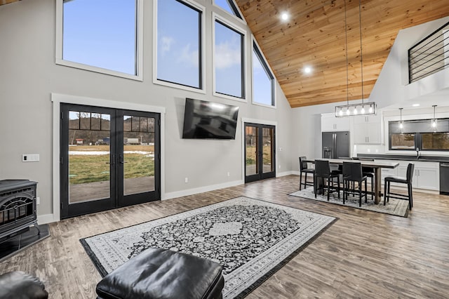 living room featuring a wood stove, french doors, high vaulted ceiling, wood-type flooring, and wood ceiling