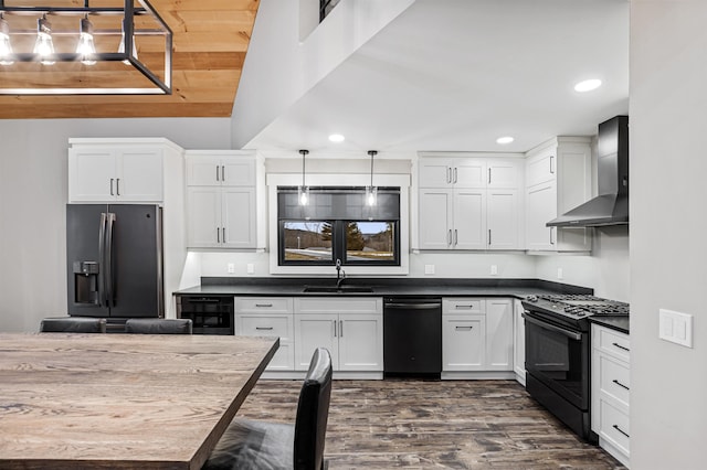 kitchen featuring pendant lighting, black appliances, white cabinets, wall chimney range hood, and sink