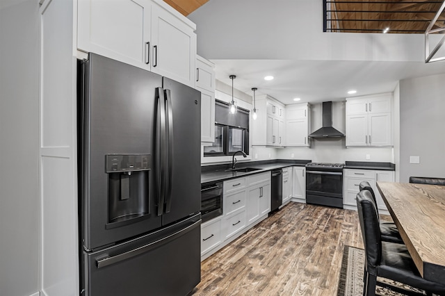 kitchen with white cabinetry, pendant lighting, black appliances, and wall chimney range hood