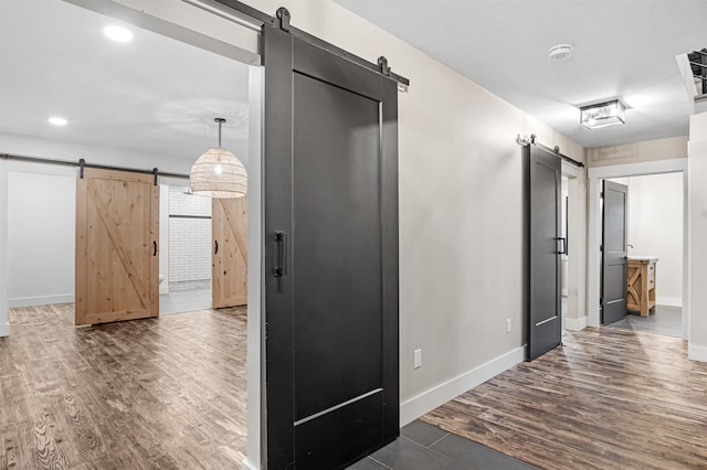 hall with a barn door and dark hardwood / wood-style flooring